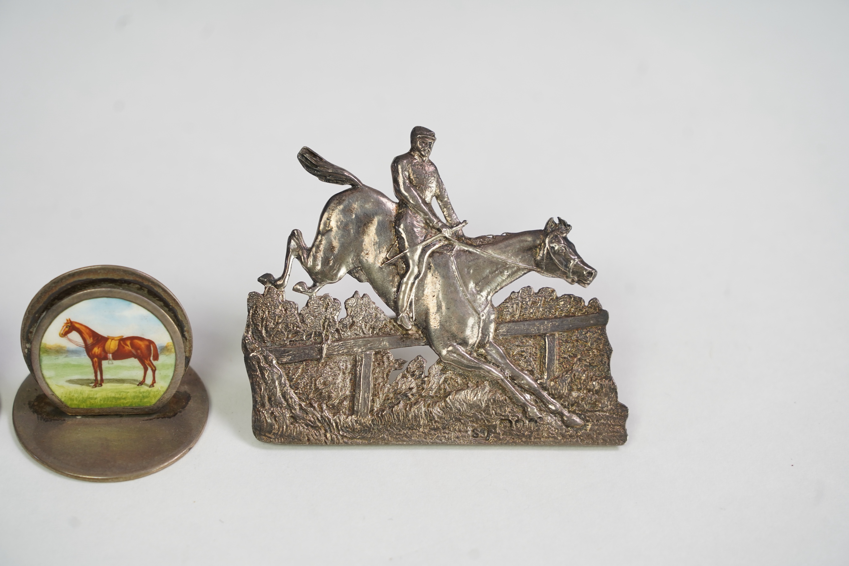 A pair of late Victorian silver menu holders, each modelled as a horse and rider leaping a fence, by Samuel Jacob, London 1894/5, height 66mm, together with a pair of Edwardian silver and enamel menu holders, each decora